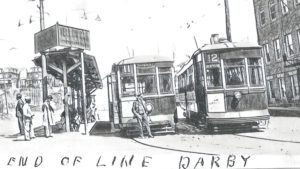 A conductor stands in front of two trolley cars idling at the transit loop in Darby Borough, sometime in the 1920s.